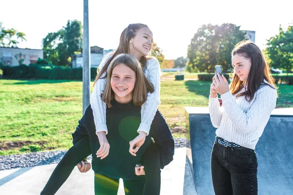 3 adolescentes 12-15 anos, brincar se divertindo, feliz, alegrar-se, gravar vídeos e fotos no telefone, no verão, primavera de outono na cidade, fins de semana. Depois da escola e da faculdade. Em jeans e blusas . — Fotografia de Stock