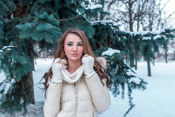 Dívka v teplém saku, v zimě na pozadí smrku a sněhu. Volné místo pro text. Emoce sebedůvěry a oddanosti. Dlouhé vlasy teplé rukavice. — Stock fotografie