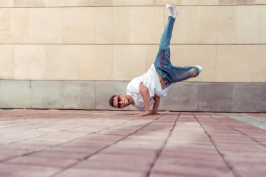 Dansçı akrobat amuda kalkıp break dans, hip hop. Summer City, arka plan duvarı. Aktif gençlik yaşam tarzı, erkek dansçı fitness break dansçısı. Tişört kotlu güneş gözlüklü. Metin için boş alan.
