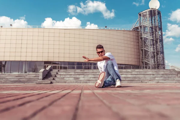 dancer dancing break dance, hip hop. Summer city, clouds background. Active youth lifestyle young male dancer fitness movement workout breakdancer. In jeans sneakers, sunglasses. Free space for text.