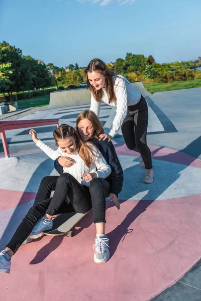 Školačky teenageři dívky, 3 přítelkyně jezdit na skateboardu, Podzim teplé svetry bavit, šťastný bavte se, hrát, relaxovat po škole, emoce radosti a potěšení z potěšení. V létě příroda města — Stock fotografie