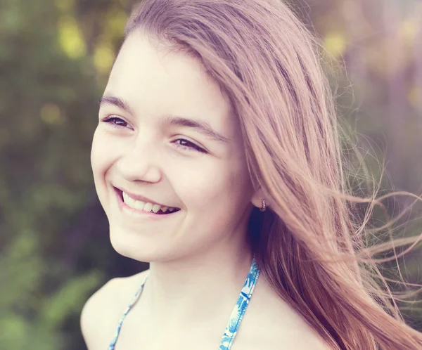Close-up portret van een kind, mooi klein tienermeisje lachend en lachend, in de zomer in de natuur, emoties van geluk, vreugde en ontspanning. Lang haar ontwikkelt zich in de wind. — Stockfoto
