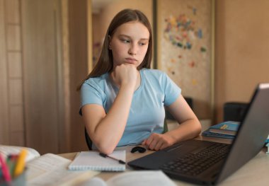 Teenage girl, serious and upset, tired and concentrated, home lessons with a laptop, video training on the Internet. Bad rating and internet error. Bad exam and social media conflict.