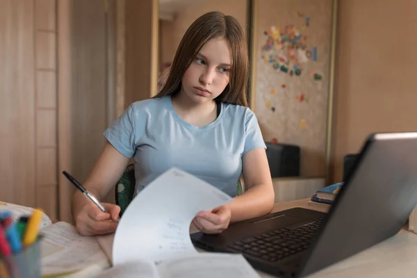 Ragazza adolescente che scrive in quaderni e appunti di incarico, educazione a casa, preparazione per il college e la scuola. Videoconferenza su Internet. Comunicazione online con un insegnante in un computer portatile . — Foto Stock