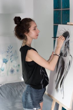 Fırçalı güzel bir kız, mutlu gülüşler, kadın silueti, resim sehpası. Evde, atölyede. Fantezi duyguları, yaratıcılığın keyfi ve ilham. Resim sanatı.