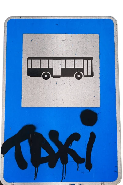 Deteriorated bus stop sign written above with spray paint is the word Taxi. White background.
