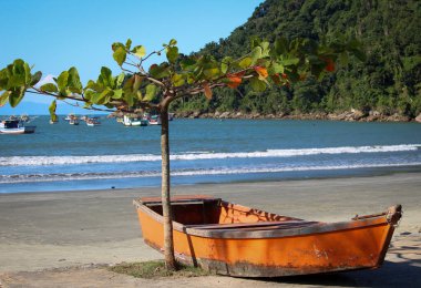 Orange little boat at the sidewalk in Praia do Pereque in Guaruja, Brazil clipart