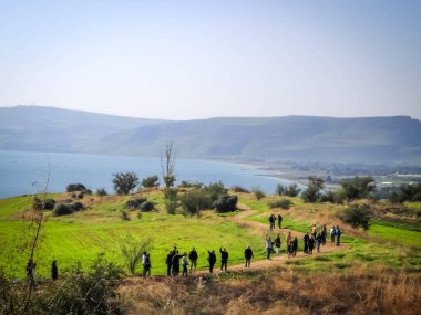 Bir grup turist güneşli bir günde Galilee Denizi 'ne gidiyorlar.