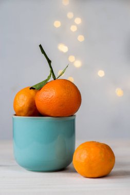 taze mandalina bokeh arka plan üzerinde mavi bir seramik kupa