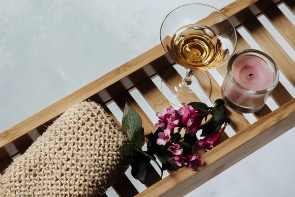 浴缸上的木制搁板 配有一杯白葡萄酒 粉红色花和天然沐浴配件 — 图库照片