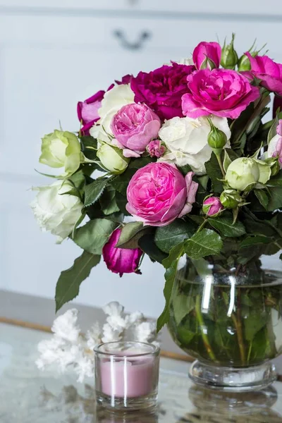Female Interior - bouquet of fragrant pink and white English roses, white coral and pink candle on the glass table