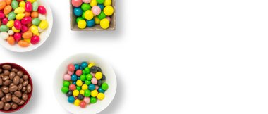 Renkli şekerler. Renkli tatlılar, şenlikli dekorasyon. Beyaz arkaplanda renkli şekerler, mesaj veya tebrik kartı için fotokopi alanı olan üst görünüm. Şeker ve tatlı kavramı. Geniş resim.