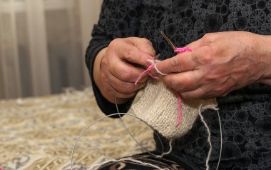 Kanepede otururken örgü şişi tutan büyükannelerin ellerinin kendi elleriyle bir şeyler yarattığı yakın çekim görüntüsü. El örgüsü beyin fonksiyonlarını geliştirir. Eski nesiller kavramı.