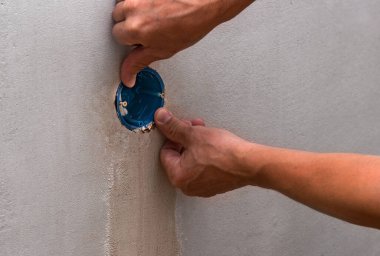 Bir ustanın elleriyle yeni yuvaları tamir etmek için plastik mavi kutular kazmak ve yerleştirmek. Yeni bir dairenin yenilenmesi..