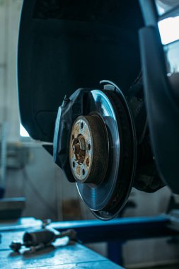 Araba servisinde, araba asansörde, tekerleği sökülmüş, fren diski ve pedleri görünür.