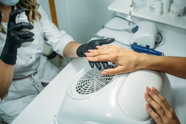 Nail salon, the master does nail care for the client. a master in a dressing gown and a mask, in the frame of the hand, moments of action with the client's nails