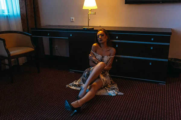 一人でホテルで夜の若い美しい女の子は 床に座っています コンセスからの夜の光 — ストック写真