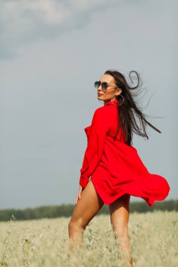 Geniş bir tarlanın ortasında duran genç ve güzel bir kız, kırmızı bir elbise giyiyor, sonbahar renkleri her yerde.!
