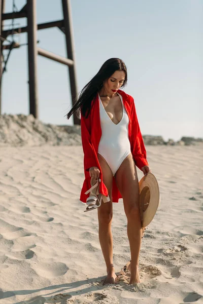 Güzel vücutlu genç bir kız, sadece beyaz kum ve mavi gökyüzü etrafında, ve üzerinde beyaz bir mayo ve güzel aksesuarlar