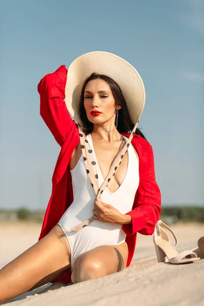 A young beautiful girl with a good figure, around only white sand and blue sky, and on her a white swimsuit and beautiful accessories