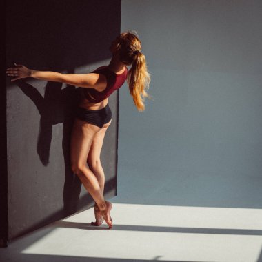 Genç bir kız, bir jimnastikçi, plastik figürlü, stüdyodaki küpleri plastikleştiriyor, pencereden gelen güneş ışığı onun üzerinde parlıyor..