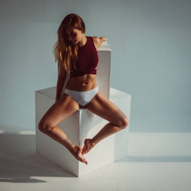 Genç bir kız, bir jimnastikçi, plastik figürlü, stüdyodaki küpleri plastikleştiriyor, pencereden gelen güneş ışığı onun üzerinde parlıyor..