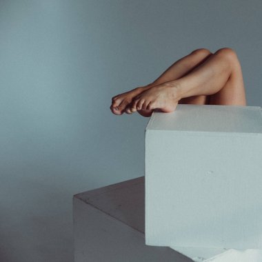 Plastik figürlü genç bir kız, stüdyoda beyaz küpleri yalıyor, plastikleri gevşetiyor, pencereden gelen güneş ışığı onun üzerinde parlıyor..