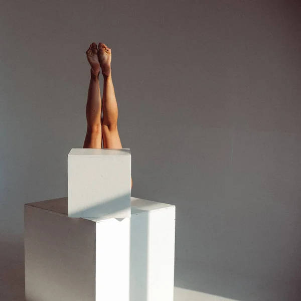 A young girl, with a plastic figure, licks on white cubes in the studio, makes plastic eases, the sunlight from the window shines on her.