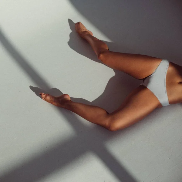 彼女の足だけが見え窓からの光が彼女の上に輝き床に絵を描く彼女の足だけが見えます — ストック写真