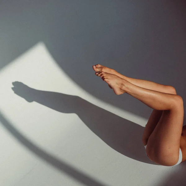 플라스틱 형상을 소녀가 스튜디오 배경에서 그녀의 다리만이 보이고 창문에서 햇빛이 — 스톡 사진
