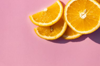 Dilimlenmiş portakal meyvesi, mavi kara zeminde izole edilmiş, pop sanatı rengi konsepti. Pembe arkaplan.