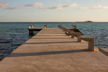 Güneşli bir günde sakin bir suyla denize giren Paved iskelesi ve arka planda denizin ortasına inşa edilmiş bir platform.