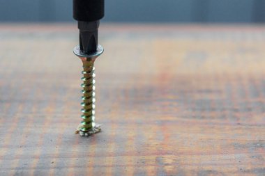 Metal vida ahşap tahta yüzeye tornavidayla tutturulmuş. ev ya da atölye onarım kavramı