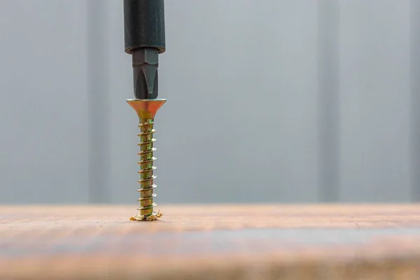 La vis métallique vissée dans la surface de la planche en bois avec tournevis. concept de réparation maison ou atelier — Photo