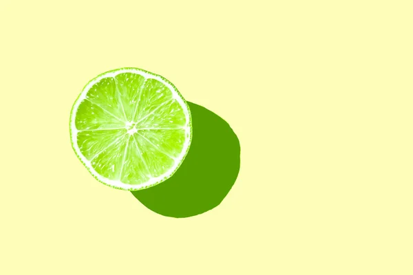 half sliced green fresh lime with hard shadow on yellow background isolated. green lime summer concept