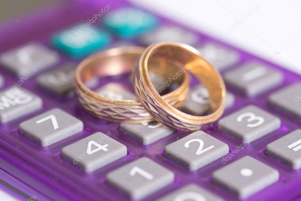 A calculator and two golden wedding rings