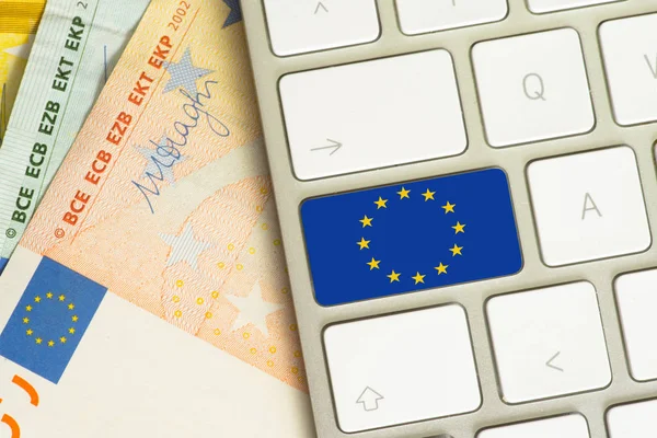 Euro bills, a computer and the flag of the European Union EU