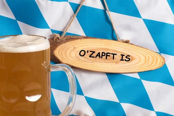 Flag of Bavaria, pitcher with beer and a sign with the slogan O Zapft is