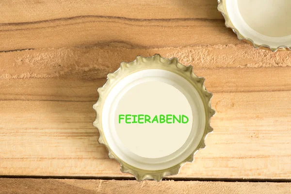 A bottle cap from a beer bottle and the word Feierabend