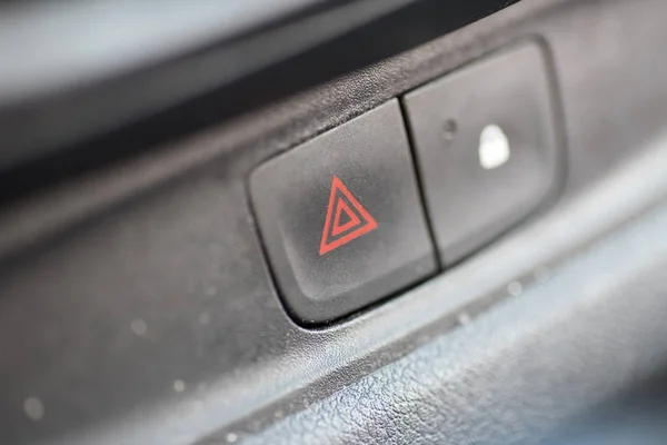 The button for hazard lights in a car