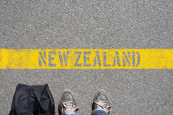 A man with a suitcase is standing on the border with New Zealand