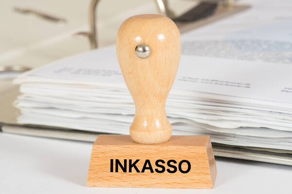 A folder with reminders and invoices and a stamp with the imprint Inkasso