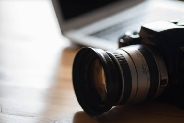 Bir analog ayna reflex fotoğraf makinesi ve ofiste bir tabloda bir laptop