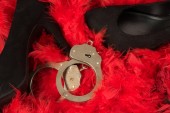 High heels and handcuffs on a base of red feathers