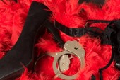 High heels, handcuffs and lingerie on a red feather pattern