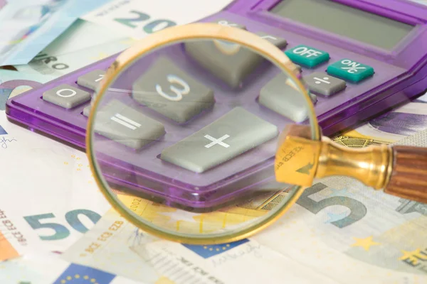 Bir hesap makinesi, büyüteç ve euro faturaları
