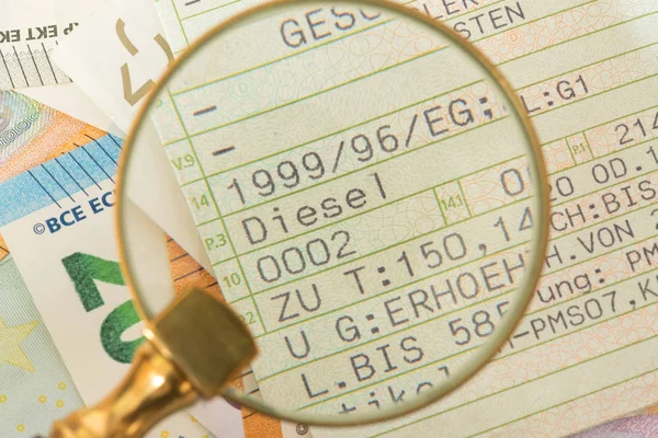 A vehicle registration for a diesel car, a magnifying glass and euro banknotes