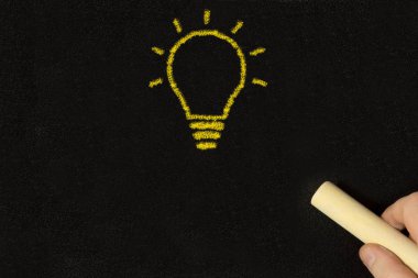 Tahtadaki bir adam bir fikrin sembolü olarak bir ampul çiziyor.