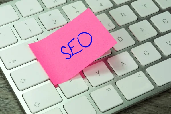 A computer and a piece of paper with the word SEO Search Engine Optimization