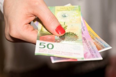 Bir kadın İsviçre Frangı banknot elinde tutar.